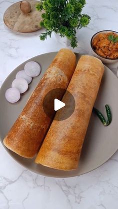 two large rolls on a plate with sauces and other food in bowls around them