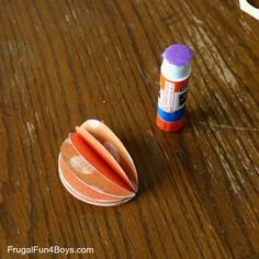 an orange object sitting on top of a wooden table next to a roll of toilet paper