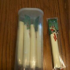 some white candles sitting in a plastic container on a wooden table next to a packaged package