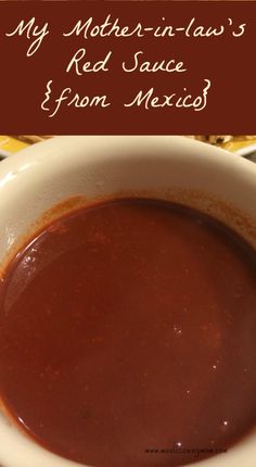 a white bowl filled with sauce sitting on top of a table next to a plate