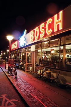 a bike parked in front of a bosco restaurant at night with its lights on