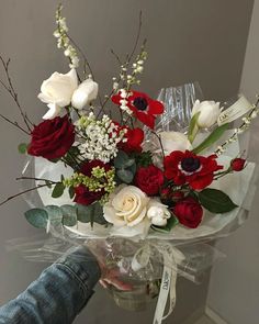 someone holding a bouquet of red and white flowers