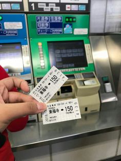 someone holding two tickets in front of a machine