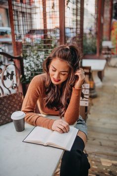 a woman sitting at a table with an open book and coffee in front of her