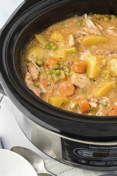 a crock pot filled with chicken, potatoes and carrots