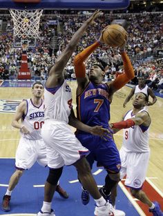 the basketball players are trying to block the ball from going into the basket in front of them