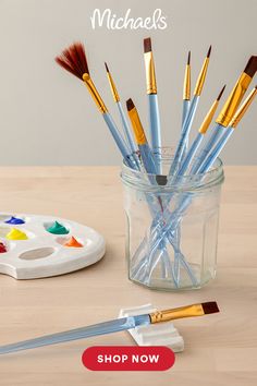 a glass jar filled with lots of paint brushes