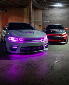 two cars parked in a parking garage with purple lights on the front and back bumpers