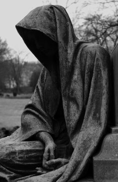 a black and white photo of a statue with a hood on it's head