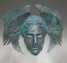 a bronze mask with wings on it's head