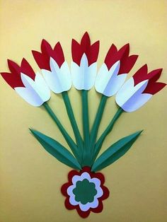 red and white paper flowers are arranged on a yellow background with a green flower in the center