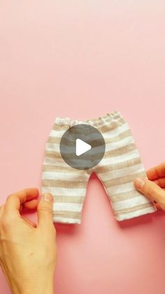 two hands holding up a pair of baby leggings to show how they are made