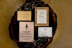 the stationery is laid out on top of the wooden table with purple flowers and greenery