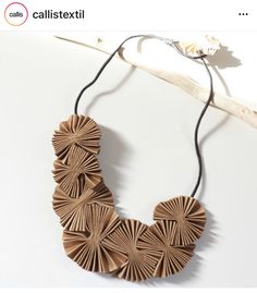 a necklace made out of brown paper on a white background with the words callistextil above it