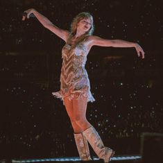 a woman is performing on stage with her arms outstretched