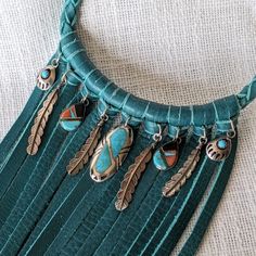 A collection of sterling silver and turquoise vintage charms have been added to a deep aqua leather fringe collar style necklace. Charms include: turquoise and sterling silver bear claw. Sterling silver feathers. Inlaid turquoise, coral and onyx teardrops, and a large oval inlaid turquoise and sterling silver centerpiece. The necklace measures approximately 18 and 1/2 inches around the neck. Fringe measures up to 9 and 1/2 inches long. Braided leather necklace closes with sterling silver hook clasp. Cool and unique statement piece!! Grass Dance Outfits, Leather Fringe Necklace, Wearable Crafts, Long Leather Necklace, Monster High Fashion, Brown Leather Necklace, Braided Leather Necklace, Monster High G3, Silver Centerpiece