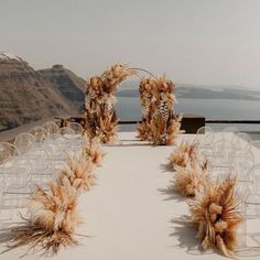 an outdoor wedding set up with chairs and pamodia flowers in front of the ocean