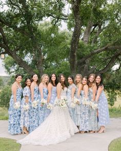 a group of women standing next to each other in front of a tree and grass field