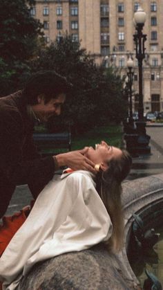 a woman laying on top of a rock next to a man