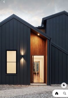 a black house with two doors and windows on the outside, in front of an open door