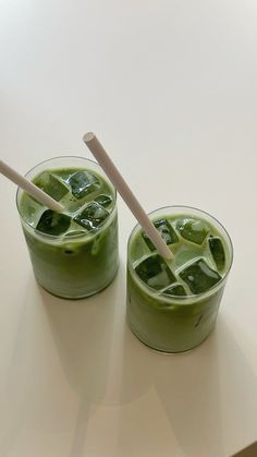 two glasses filled with green liquid and straws