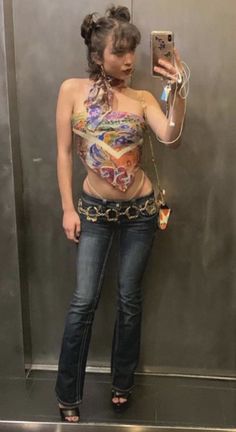 a woman taking a selfie in front of a mirror wearing jeans and a bra