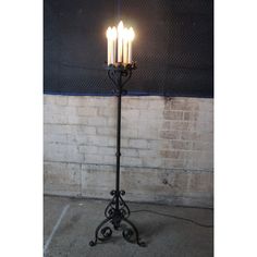 four candles are lit on an iron stand in front of a brick wall and concrete floor