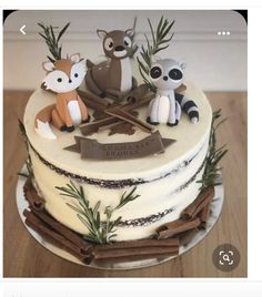 a cake decorated with three little raccoons on top of a wooden table next to an arrow