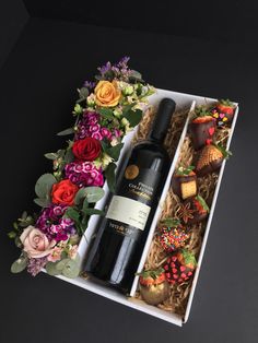 a bottle of wine and some chocolates in a box with flowers on the side