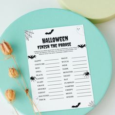 a printable halloween finish the phrase game sits on a plate next to some dried flowers