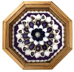 a wooden frame with an intricate design in the center and shells on the bottom, along with other decorative objects