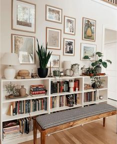 a bookshelf filled with lots of books next to a white wall covered in pictures