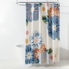 a shower curtain with colorful flowers on it in a white bathtub next to a toilet