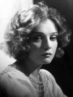 black and white photograph of a woman with curly hair wearing a dress looking off to the side