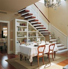 a dining room table set for two under the stairs