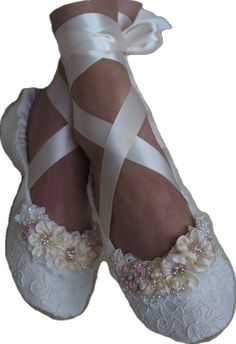 a pair of white shoes with flowers and ribbons on the toes, tied in ribbon