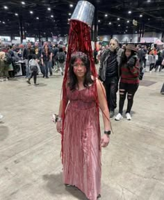 a woman in a red dress with a bucket on her head and blood dripping from the top