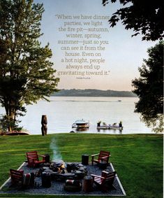 there is a fire pit with chairs around it in the grass next to some water