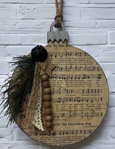 a wooden clock with music sheets and bells hanging on a wall next to a brick wall