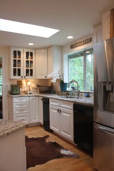 a large kitchen with white cabinets and stainless steel appliances, along with a cow rug on the floor