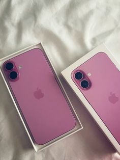 two pink iphones sitting in a box on top of a white sheet covered bed