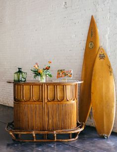 a table with vases and flowers on it next to two surfboards