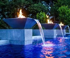 an outdoor fire pit in the middle of a pool with water shooting from it's sides