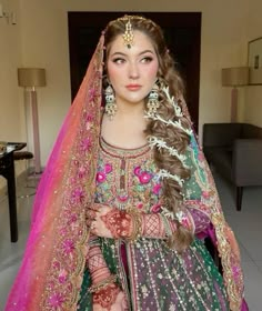 a woman in a green and pink bridal outfit with long hair wearing a veil