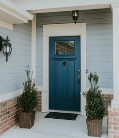 a blue front door with two potted plants