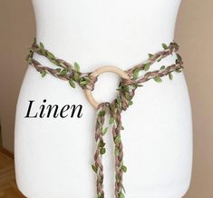 a white mannequin torso with a wooden ring and green leaves on it's belt