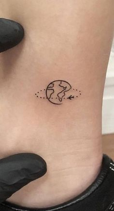 a small earth tattoo on the side of a woman's ribcage is shown