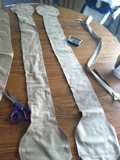 several pieces of fabric laid out on top of a wooden table with scissors and tape