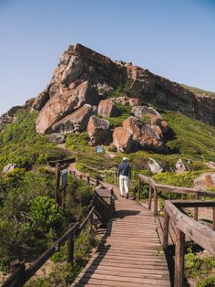 a person walking down a wooden path near some rocks