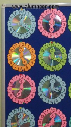 a clock made out of cd's on a blue background with numbers and animals